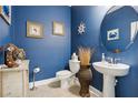 Charming powder room with blue walls, decorative mirror, and pedestal sink at 977 Timberview Rd, Clermont, FL 34715