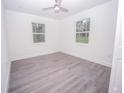 Bright bedroom with two windows offering natural light and modern gray wood laminate flooring at Lot 19 Indian Estates Cr 423, Lake Panasoffkee, FL 33538