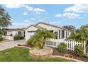 Well-maintained home featuring a white picket fence, manicured lawn, and charming landscaping at 2277 Whisper St, The Villages, FL 32162