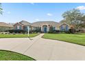 Charming single-story home boasts vibrant blue shutters, a well-manicured lawn, and an inviting entrance at 10230 Barrington Ct, Leesburg, FL 34788