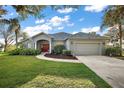 Well-maintained single-story home with a lush front lawn, two-car garage, and a vibrant red entry door at 10606 Masters Dr, Clermont, FL 34711