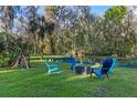 Inviting backyard space with a fire pit, Adirondack chairs, and views of a peaceful pond surrounded by lush greenery at 11243 Dead River Rd, Tavares, FL 32778