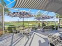 Relaxing screened-in patio with patio furniture and awning, offering beautiful views of the golf course and blue skies at 12390 Se 176Th Loop, Summerfield, FL 34491