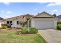 Traditional home featuring a well-manicured lawn, concrete driveway, and a two-car garage at 1273 Oak Forest Dr, The Villages, FL 32162