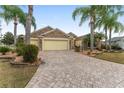 Charming front exterior with paver driveway, lush landscaping, and a well-maintained lawn, offering inviting curb appeal at 1312 Patrick Pl, The Villages, FL 32162