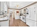 Classic kitchen with white cabinets and appliances, complemented by wood-look flooring and neutral walls at 14100 Ne 46Th St, Silver Springs, FL 34488