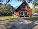 A-frame cabin featuring wood siding, a deck, and ample windows for natural light, nestled on a spacious lot at 14415 County Road 448, Tavares, FL 32778