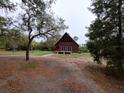 Rustic cabin showcasing a charming facade with a wooden deck and large windows amidst a serene, tree-filled setting at 14415 County Road 448, Tavares, FL 32778