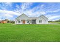 Inviting single-story home features a light gray exterior, covered porch, and a sprawling green lawn at 1679 E County Road 462, Wildwood, FL 34785