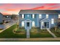 Beautiful townhome featuring a covered porch, colorful architecture, and manicured lawn at dusk at 559 Juniper Springs Dr, Groveland, FL 34736