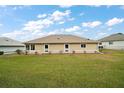 Backyard view of a cozy single-story house with well-maintained green lawn at 11053 Se 174Th Loop, Summerfield, FL 34491