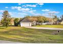 Spacious home featuring a two-car garage and a long driveway, set on a large lot with mature trees and lush green grass at 1603 Brookstone Ln, Fruitland Park, FL 34731