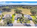 Aerial view of one-story home with large manicured lawn and a golf course just beyond the trees at 16611 Spring Park Dr, Clermont, FL 34711