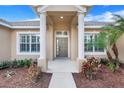 Inviting front entrance with a light gray door, white columns, shutters, and lush landscaping at 16611 Spring Park Dr, Clermont, FL 34711