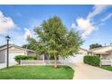 Charming single-story home featuring a well-manicured lawn, mature tree, and a classic white picket fence at 16865 Se 94Th Sunnybrook Cir, The Villages, FL 32162