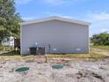 View of home's exterior showing the AC unit, septic tanks, gray vinyl siding, and well-maintained outdoor space at 17442 Eve Dr, Montverde, FL 34756