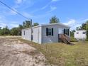 The side view of a single-Gathering home with gray siding, black shutters, and a small wooden porch, surrounded by grass and trees at 17442 Eve Dr, Montverde, FL 34756