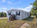 Charming single-Gathering home with gray siding, black shutters, small porch, a well-maintained lawn, set against a blue sky at 17442 Eve Dr, Montverde, FL 34756