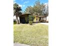 Single-story home with a covered carport, screened porch, and spacious green lawn at 224 Westwood Dr, Leesburg, FL 34748
