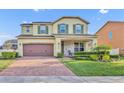 Charming two-story home featuring a brick-paved driveway, manicured lawn, and an inviting front porch at 2727 Retriever Dr, Clermont, FL 34711