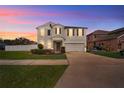 Charming two-story home with a gray exterior, well-maintained landscaping, and a two-car garage at dusk at 303 Red Kite Dr, Groveland, FL 34736