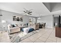 Spacious living room and dining room area with tile flooring, modern lighting, and a comfortable sectional at 303 Red Kite Dr, Groveland, FL 34736