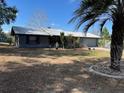 Single-story house with metal roof, front yard, and a greenhouse in the background at 37149 Grays Airport, Lady Lake, FL 32159