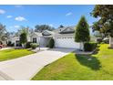 Well-manicured lawn and landscaping surround this single-story home with a two-car garage and concrete driveway at 8294 Se 177Th Winterthur Loop, The Villages, FL 32162