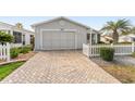 A home featuring a brick-paved driveway leading to a one-car garage and meticulously kept landscaping at 9312 Se 172Nd Wayside Pl, The Villages, FL 32162