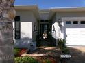 Close up of a charming house entrance featuring a decorative gate, potted plants, and brick walkway at 10173 Julia Isles Ave, Oxford, FL 34484