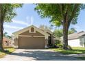 Inviting house boasts mature shade trees, a two-car garage, and a cozy front porch at 10910 Rushwood Way, Clermont, FL 34714