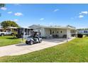 Charming home exterior with a well-manicured lawn, golf cart, and covered parking area at 1523 W Schwartz Blvd, The Villages, FL 32159