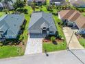 Aerial view of house with gray roof, brick driveway, well-manicured lawn, mature landscaping, and neighboring homes at 17504 Se 119Th Cir, Summerfield, FL 34491