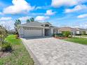 Charming home with a brick driveway, lush green lawn, mature landscaping, and a two-car garage at 17504 Se 119Th Cir, Summerfield, FL 34491