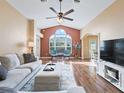 Bright living room featuring vaulted ceilings, hardwood floors, a ceiling fan, and a large window at 1904 Augustine Dr, The Villages, FL 32159