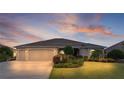 Lovely single-story home featuring a well-manicured lawn and an attached two-car garage at dusk at 2935 Cedar Grove Loop, The Villages, FL 32163