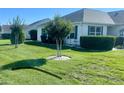 Well-manicured front yard features vibrant green grass, trimmed bushes, and a decorative tree at 3067 Southern Trce, The Villages, FL 32162