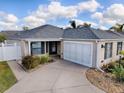 Charming single-story home with a manicured lawn, two-car garage, neutral siding, and an inviting front door under a bright sky at 591 Statesburg St, The Villages, FL 32162