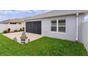 Exterior view of home showcasing a screened-in lanai, well-maintained lawn, and a concrete patio at 5934 Kaplan Ct, The Villages, FL 32163