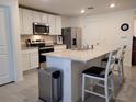 Modern kitchen features white cabinetry, stainless steel appliances, granite countertops, and an island with seating at 7133 Sw 135Th Pl, Ocala, FL 34473