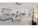 Bright and airy living room featuring neutral tones, ceiling fan, and seamless transition to dining area at 731 Hernandez Dr, The Villages, FL 32159