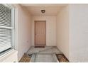 Covered front porch with peach colored entry door and a decorative stone and concrete walkway at 731 Hernandez Dr, The Villages, FL 32159