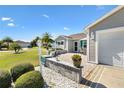 Close up of a home's front yard with a well-manicured lawn, shrubs, and a cozy front patio area at 909 Abaco Path, The Villages, FL 32163