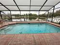 Screened-in pool overlooking a serene lake, perfect for relaxation and outdoor enjoyment at 12066 Se 60Th Avenue Rd, Belleview, FL 34420