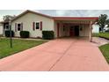 A quaint home featuring a carport with red doors and a salmon-colored driveway at 1234 E Schwartz Blvd, Lady Lake, FL 32159