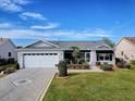 Inviting single-story home featuring a well-maintained lawn, decorative driveway, and an attached two-car garage at 1377 Eagle Ridge Dr, The Villages, FL 32162