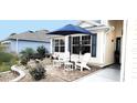 Cozy front patio area with white Adirondack chairs and a blue umbrella at 1670 Kensington Pl, The Villages, FL 32162