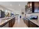 Open-concept kitchen with dark wood cabinetry, granite countertops, island seating, and a view into the living space at 17369 Blazing Star Cir, Clermont, FL 34714