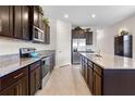 A bright kitchen featuring dark wood cabinets, granite countertops, tile flooring, and stainless steel appliances at 17369 Blazing Star Cir, Clermont, FL 34714