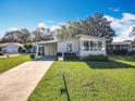 Charming single-story home featuring well-maintained landscaping and a covered carport on a sunny day at 25546 Belle Alliance, Leesburg, FL 34748